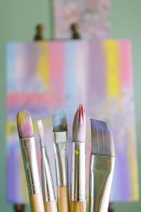 Home Art brushes with abstract painted canvas in vibrant colors.